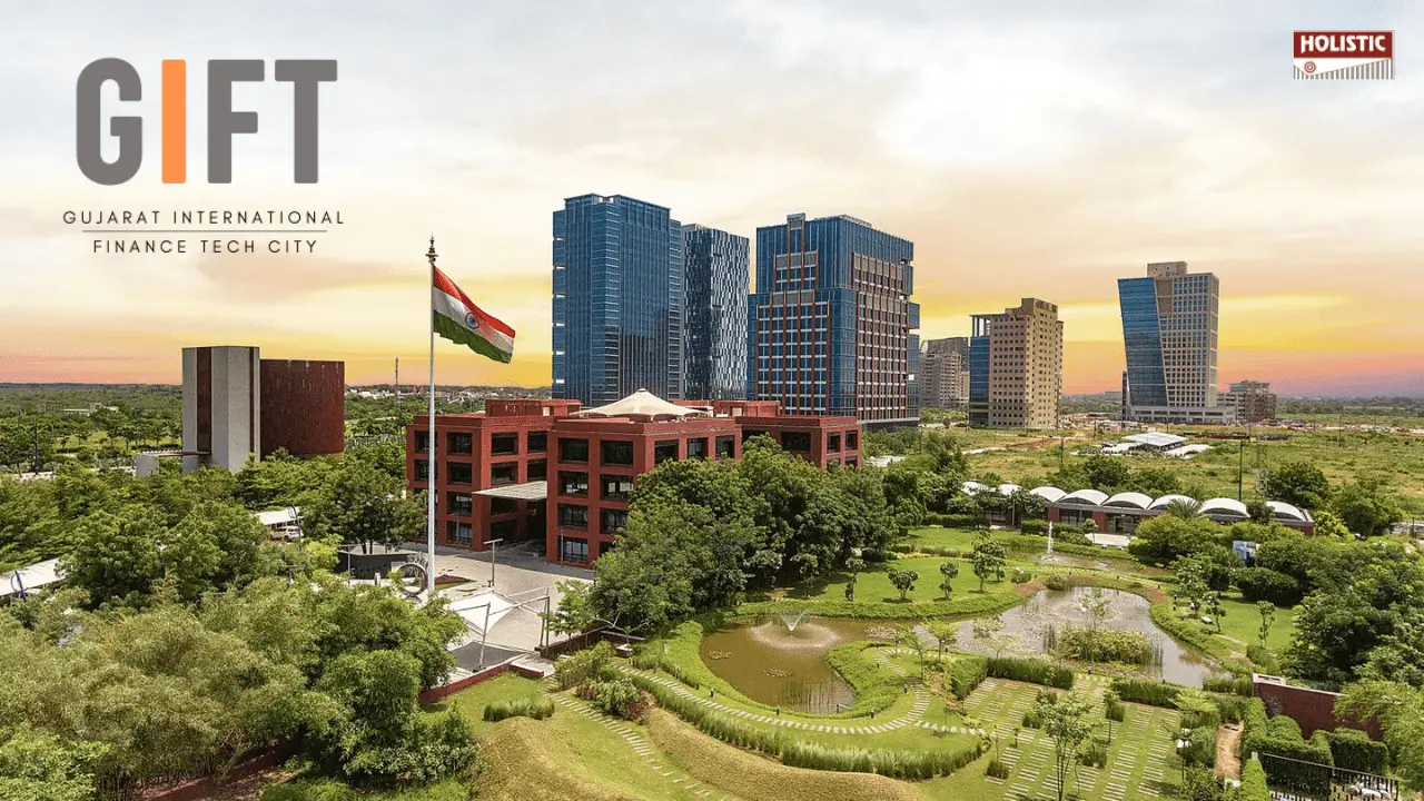 Aerial view of Gujarat International Finance Tech City with modern skyscrapers against a sunset sky, lush green landscape, and an Indian flag. Text reads "Click here to read more."